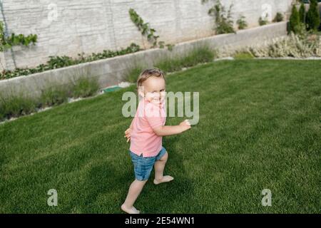 Portrait d'un petit garçon heureux qui court autour d'un jardin. Enfant souriant s'amuser dans un parc. Banque D'Images