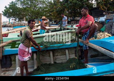 Tangalle, Sri Lanka: Les pêcheurs réparent les filets sur les bateaux de la plage de la ville Banque D'Images