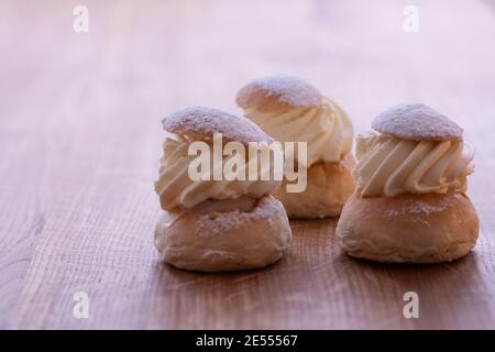 Trois pâtisseries suédoises traditionnelles, la semla, sur une table en bois. Cette pâtisserie est composée d'un petit pain à deux couches, farci de pâte d'amande sous la crème fouettée Banque D'Images