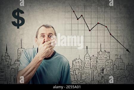 Un homme à la retraite d'âge moyen choqué, regardant de grands yeux, couvre sa bouche avec la main. Stupéfait et surpris en raison de la récession. Concept de crise économique, valeur boursière Banque D'Images