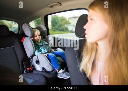 Maman a besoin de conduire une voiture et regarde en arrière son fils Banque D'Images