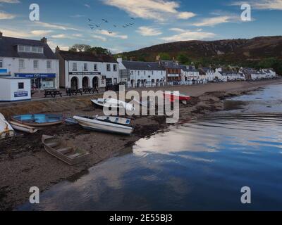 Village côtier sur l'île de Skye avec des boutiques bordées front d'eau et montagnes derrière Banque D'Images