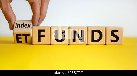 Fonds indiciels vs symbole ETF. Homme d'affaires transforme un cube et change les mots « ETF » en « Index funds ». Belle table jaune, fond blanc, espace de copie. Bus Banque D'Images