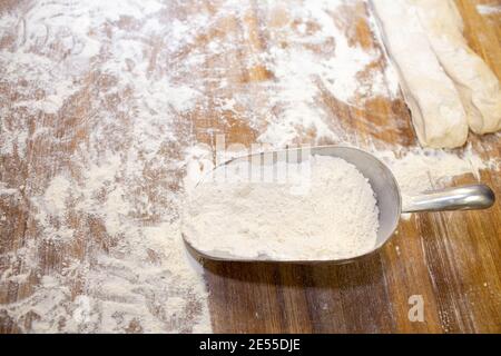 Farine de blé sur une table en bois et une cuillère de mesure. Banque D'Images