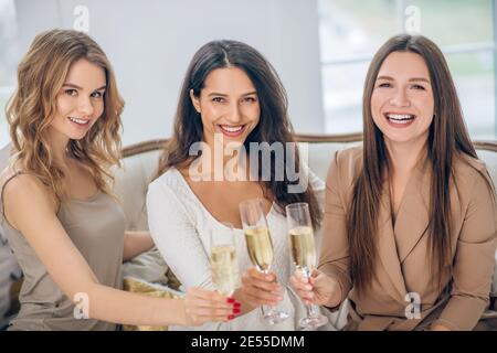 Trois jeunes filles ayant une fête de poule et buvant du champagne Banque D'Images