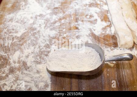 Farine de blé sur une table en bois et une cuillère de mesure. Banque D'Images