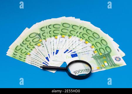 Billets en euros et loupe sur fond bleu Banque D'Images