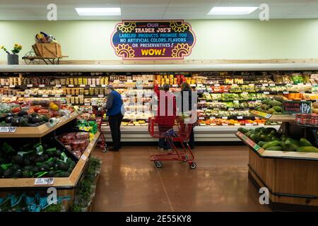 Trois personnes magasinent dans la section des produits et présentent des légumes frais dans Trader Joe's. Wichita, Kansas, États-Unis Banque D'Images