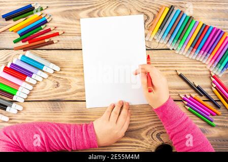 La petite fille se prépare à peindre sur une feuille de papier vierge. Le dessin est fait par un enfant avec des crayons de couleur ou des stylos-feutres. Dessin des enfants. Voir fr Banque D'Images