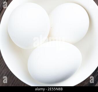 Gros plan des œufs de poulet avec une coquille blanche dans une tasse blanche. Vue de dessus. La nourriture. Banque D'Images