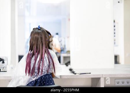 une petite fille teint ses cheveux violets dans un salon de coiffure Banque D'Images