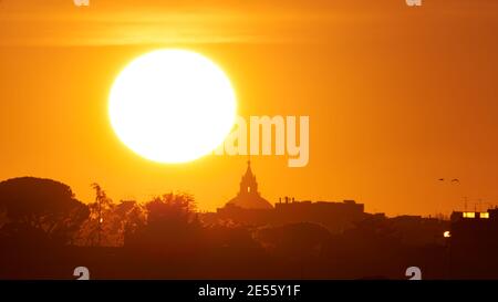 Coucher de soleil sur la basilique Saint-Pierre, symbole du christianisme et la plus grande et la plus haute église du monde. Vue télescopique réelle du soleil derrière St Pierre Banque D'Images