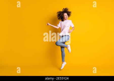 Photo portrait vue du corps de la femme jouant sur l'air guitare sautant isolée sur fond jaune vif Banque D'Images