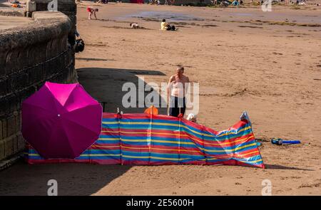 Un couple sur la plage de Scarborough vu derrière leur coupe-vent et parasol. Banque D'Images