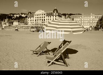 Chaise longue en bois de plage et parasol avec frange. Trouville-sur-Mer (Normandie, France). Photo historique sépia. Banque D'Images