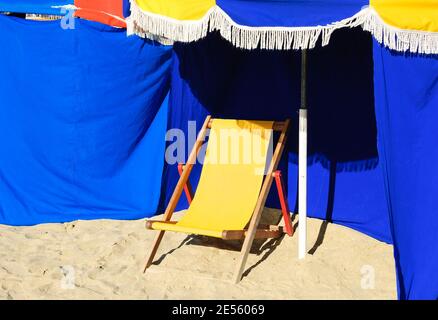Chaise longue en bois de plage et parasol avec frange. Trouville-sur-Mer (Normandie, France). Sélection de l'accent sur le parapluie. Banque D'Images