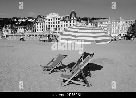 Chaise longue en bois de plage et parasol avec frange. Trouville-sur-Mer (Normandie, France). Photo historique noir blanc. Banque D'Images