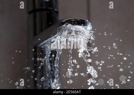 Robinet d'eau cassé dans le lavabo de la salle de bains. Projections d'eau du robinet argenté Banque D'Images