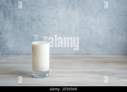 Lait dans un long verre transparent sur fond gris-bleu. Vue latérale avec espace de copie. Banque D'Images