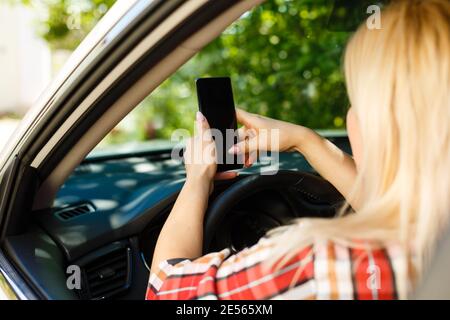 Une jeune femme regarde son smartphone dans une voiture. Banque D'Images