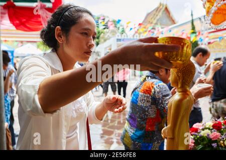 Une femme verse de l'eau sur une statue de Bouddha pendant Songkran, nouvel an thaïlandais, à Bangkok, en Thaïlande. Banque D'Images