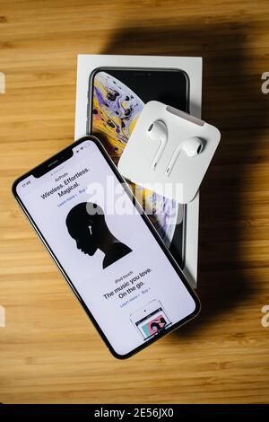 Paris, France - 2 octobre 2018: Déballage du dernier Apple Computers iphone smartphone avec face ID présentant la page web d'AirPods et le tout nouveau Apple Computers écouteurs EarPods écouteurs avec connecteur Lightning - arrière-plan en bois Banque D'Images