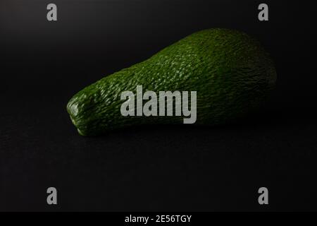 Avocat vert mûr unique isolé sur fond noir Banque D'Images