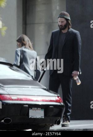 Exclusif !! Un regard triste Keanu Reeves ouvre la porte d'une voiture pour une femme compagnon après une visite de sa maison de Hollywood Hills à CA. L'acteur a montré à la femme en train de regarder les rénovations qu'il a fait à sa maison de style moderne depuis plusieurs mois. 3/4/07 [[ral]] Banque D'Images