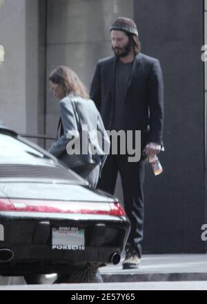 Exclusif !! Un regard triste Keanu Reeves ouvre la porte d'une voiture pour une femme compagnon après une visite de sa maison de Hollywood Hills à CA. L'acteur a montré à la femme en train de regarder les rénovations qu'il a fait à sa maison de style moderne depuis plusieurs mois. 3/4/07 [[ral]] Banque D'Images