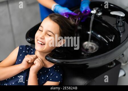 une petite fille teint ses cheveux violets dans un salon de coiffure Banque D'Images