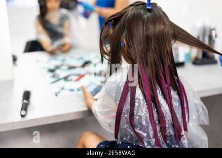 une petite fille teint ses cheveux violets dans un salon de coiffure Banque D'Images