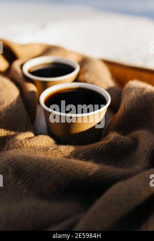 Deux tasses de café sur un foulard dans la forêt enneigée. Arrière-plan flou Banque D'Images