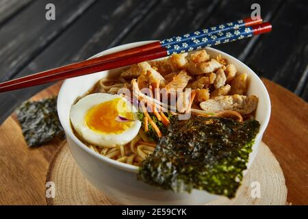 Soupe japonaise de ramen avec poulet, œuf, ail et nouilles sur fond de bois sombre. Nouilles asiatiques miso Ramen Banque D'Images