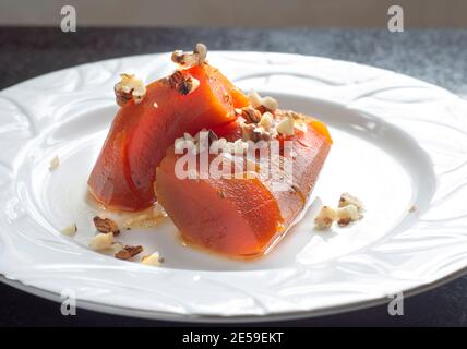 Dessert à la citrouille avec des saupoudrées de noix cuites au sucre vapeur, sur une assiette blanche. Banque D'Images