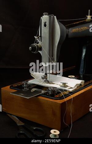 Machine à coudre et pièces sur fond sombre. Banque D'Images
