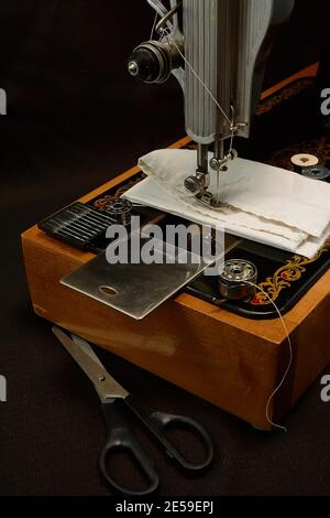 Machine à coudre et pièces sur fond sombre. Banque D'Images