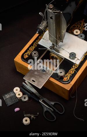 Machine à coudre et pièces sur fond sombre. Banque D'Images