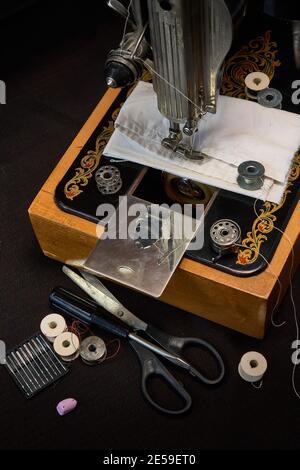 Machine à coudre et pièces sur fond sombre. Banque D'Images