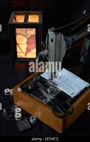 Machine à coudre et pièces sur fond sombre Banque D'Images