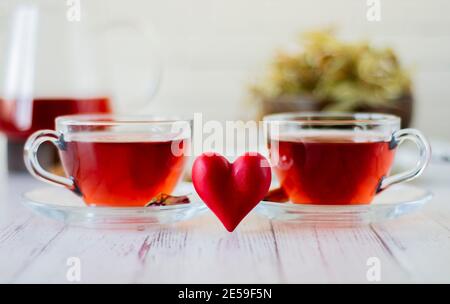 Variétés d'herbes brassées dans une théière en verre sur bois devant le mur blanc. Tilleul, fleur de grenade, thé vert, graine de raisin, feuilles d'olive, St cannelle Banque D'Images