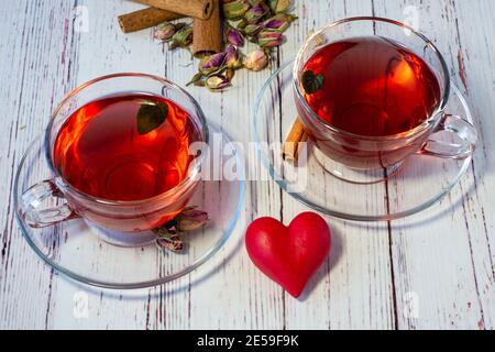 Variétés d'herbes brassées dans une théière en verre sur bois devant le mur blanc. Tilleul, fleur de grenade, thé vert, graine de raisin, feuilles d'olive, St cannelle Banque D'Images