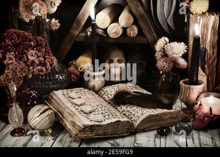 Encore la vie avec le vieux livre de grimoire de sorts magiques, runes et mauvaises bougies sur table de sorcière. Arrière-plan ésotérique, gothique et occulte, pas de symboles étrangers, Banque D'Images