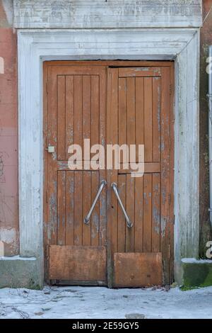 Une vieille porte en bois, ensacheuse et fermée. Grande porte avec poignées en acier inoxydable et sonnette. Personne. Banque D'Images