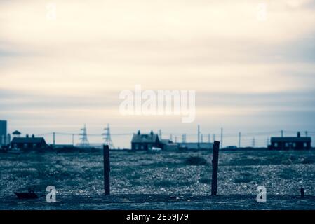 Maisons et pylônes avec grand ciel sur la plage de Dungeness. Kent, Angleterre. Banque D'Images