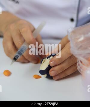 Processus de décoration de gâteau. Baker utilise des outils pour sculpter des motifs fondants : art comestible, design de gâteau, décoration de gâteau. Mise au point sélective des outils frontaux et de la main Banque D'Images