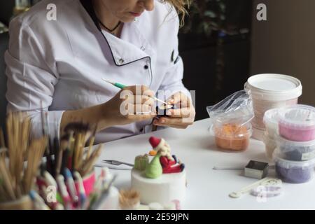 Processus de décoration de gâteau. Baker utilise des outils pour sculpter des motifs fondants : art comestible, design de gâteau, décoration de gâteau. Mise au point sélective des outils frontaux et de la main Banque D'Images