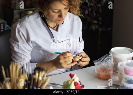 Processus de décoration de gâteau. Baker utilise des outils pour sculpter des motifs fondants : art comestible, design de gâteau, décoration de gâteau. Mise au point sélective des outils frontaux et de la main Banque D'Images