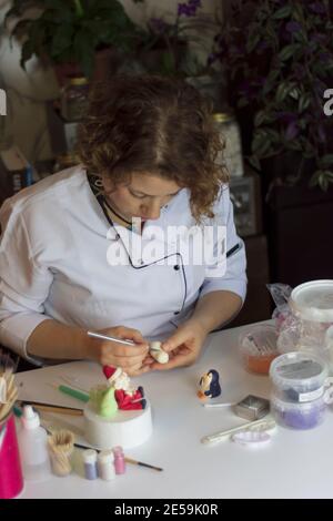 Processus de décoration de gâteau. Baker utilise des outils pour sculpter des motifs fondants : art comestible, design de gâteau, décoration de gâteau. Mise au point sélective des outils frontaux et de la main Banque D'Images