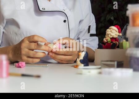 Processus de décoration de gâteau. Baker utilise des outils pour sculpter des motifs fondants : art comestible, design de gâteau, décoration de gâteau. Mise au point sélective des outils frontaux et de la main Banque D'Images