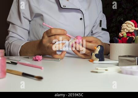 Processus de décoration de gâteau. Baker utilise des outils pour sculpter des motifs fondants : art comestible, design de gâteau, décoration de gâteau. Mise au point sélective des outils frontaux et de la main Banque D'Images